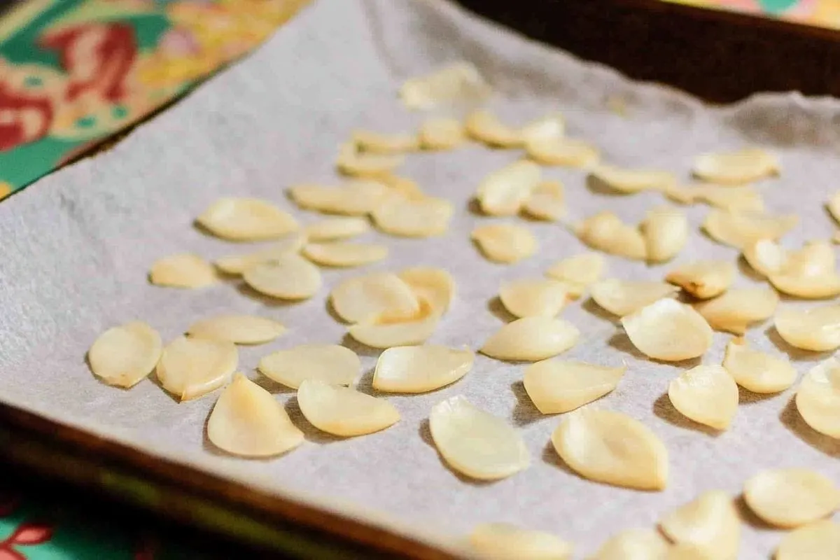 sliced garlic pieces spread out on baking paper